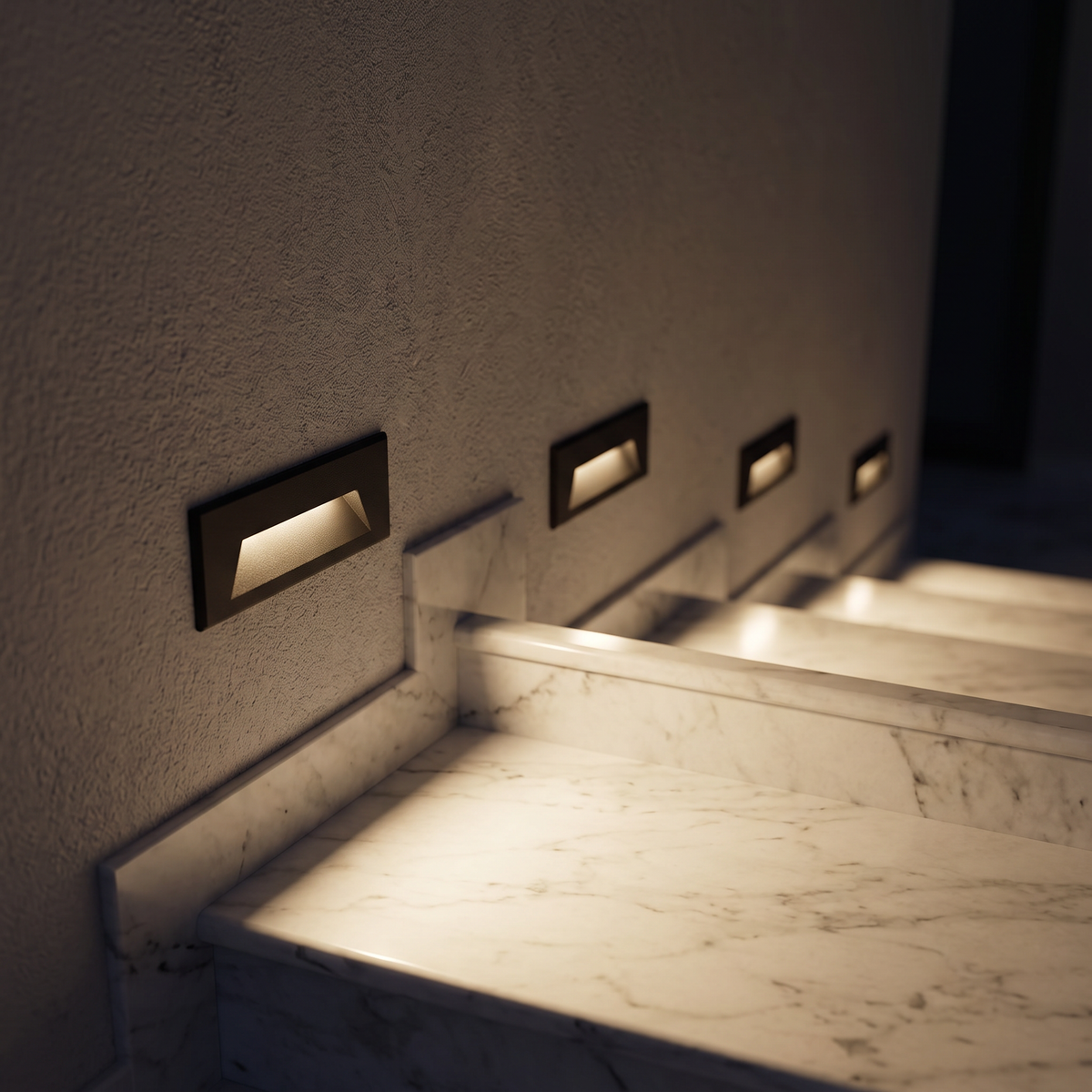 Rectangular LED step lights recessed into the wall beside an indoor marble staircase at night, each lighting a step with warm light